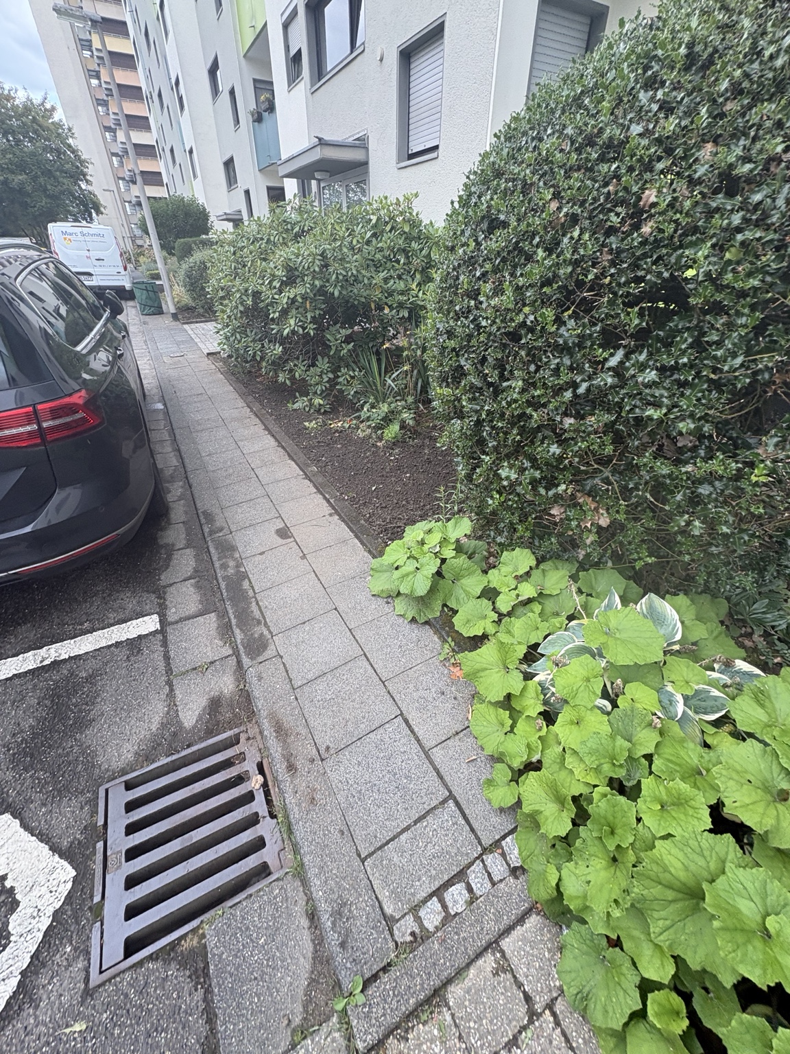 Geschnittene Hecken und gepflegte Beete vor einer Wohnanlage