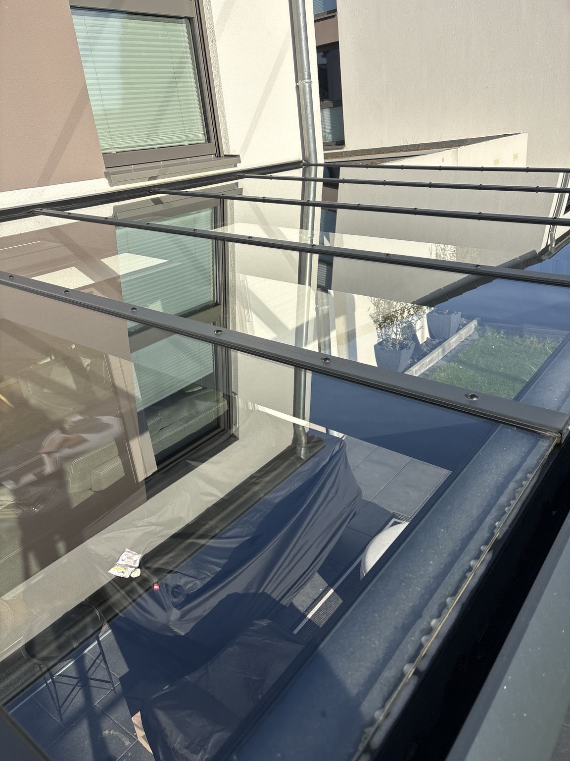 Terrassenglasdach mit dunklen Trägern und klaren Spiegelungen
